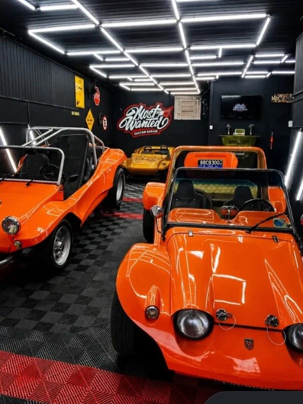 Dois buggies laranja no estúdio da Most Wanted, com o logo grafitado na parede